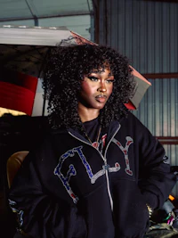 a woman in a black hoodie standing next to an umbrella